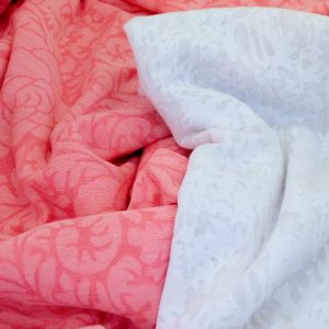 PINK AND WHITE TONAL PATTERNED FABRIC DRAPED NEXT TO EACH OTHER.
